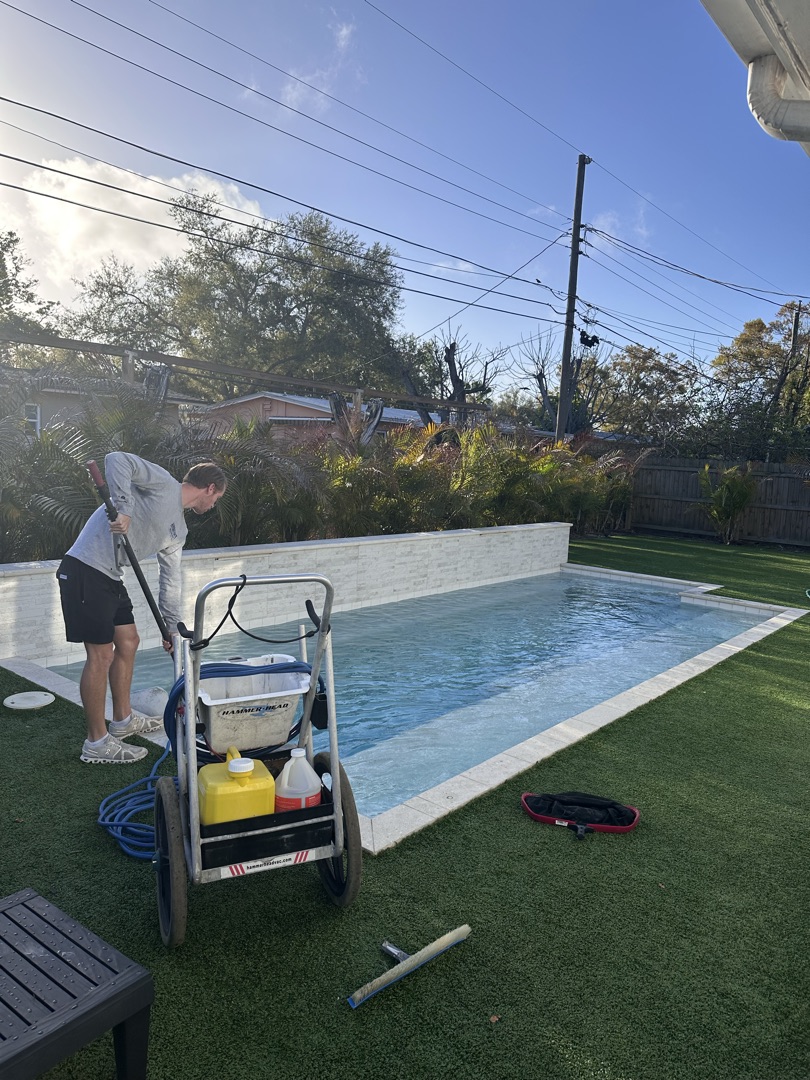 Sunshine Pool Group technician brushing a residential pool during weekly service in Pinellas County