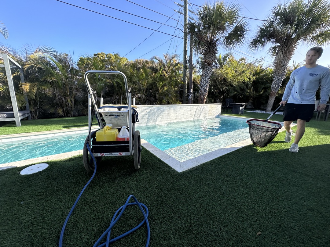 Sunshine Pool Group technician skimming a pool with a net — professional pool cleaning in Pinellas County